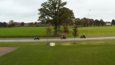 Drone-view-following-motorbikes-between-green-grass-fields