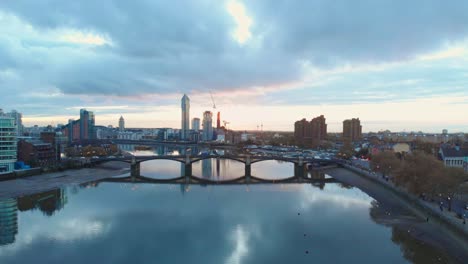 dolly-forwards-drone-shot-of-traffic-on-Battersea-bridge-and-Chelsea-harbour-London-at-sunset