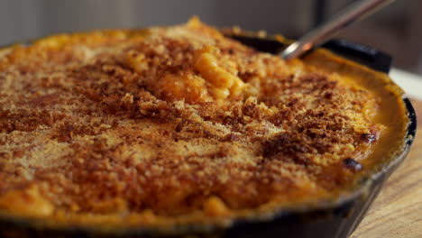 Fork-dig-in-a-cast-iron-skillet-filled-with-mac-and-cheese,-a-classic-American-dish,-baked-in-the-oven-with-crispy-breadcrumbs-on-top