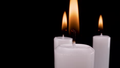 Makro-Nahaufnahme-Weiße-Brennende-Kerzen-Auf-Schwarzem-Hintergrund,-Die-Sich-Drehen,-Um-4k-Filmmaterial-Erinnerung-Anzuzeigen