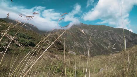 Low-angle-slow-motion-mountain-view-with-mountain-ridges,-white-clouds-and-a-blue-sky-in-a-valley-at-the-Fagaras-Carpathian-Mountains