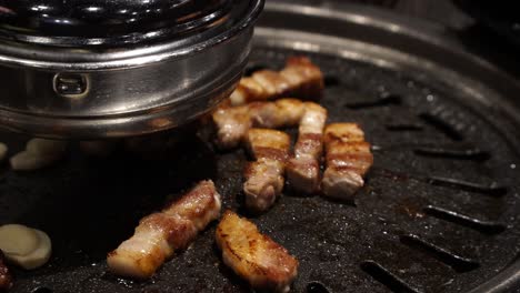 Pork-belly-getting-seared-on-traditional-Korean-barbecue-in-restaurant