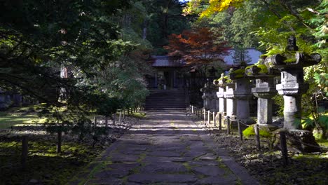 Slow-dolly-out-from-path-inside-beautiful-Japanese-temple-lined-with-stone-pillars