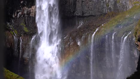 Slide-reveal-of-beautiful-tall-waterfall-with-rainbow
