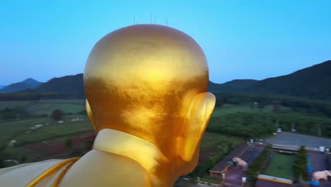 4k-Aerial-Face-Detail-shot-of-a-Biggest-Luang-Pu-Thuat-statue-in-the-world-surrounded-by-mountains-of-Khao-Yai-at-dawn-in-Thailand