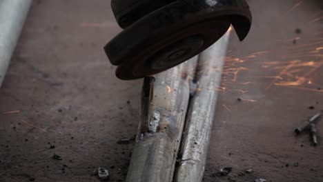 Remove-excess-weld-metal-in-iron-pipes-and-get-the-smooth-finishing-of-the-welding,-using-an-electric-hand-grinder-by-the-handyman-outdoor-slow-motion-clip