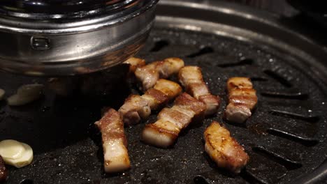 Grilling-Pork-Belly-On-A-Korean-Table-Top-BBQ-Grill-In-A-Traditional-Samgyeopsal-Restaurant---close-up