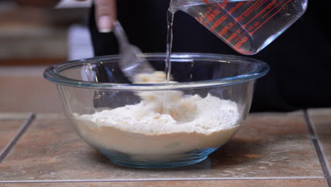 Mixing-and-stirring-water-into-a-dry,-organic-Kamut-flour-mix-with-a-fork---isolated-close-up