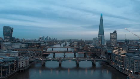 Dolly-forward-drone-shot-over-the-Thames-London-towards-the-shard-and-Canary-Wharf-at-blue-hour