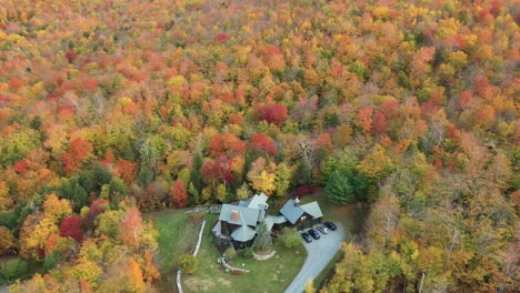Aerial-view-of-countryside-house-in-colorful-autumn-forest,-scenic-landscape-of-New-England-USA,-drone-shot