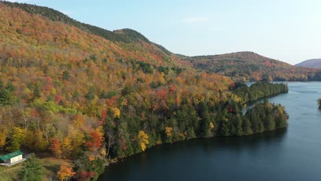 Heavenly-Lakefront-and-Colorful-Autumn-Landscape-in-a-Rural-New-England,-Vermont-USA,-Aerial-View,-Vivid-Forest-and-Calm-Water,-Drone-Shot