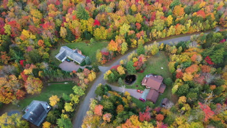 Countryside-Mansions-in-Colorful-Autumn-Landscape-of-Vermont-USA,-Aerial-View-of-Flashy-Vivid-Foliage-and-Rural-Road,-Drone-Shot