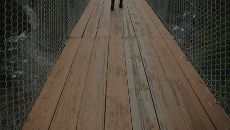 Back-View-Of-Millennial-Woman-On-Suspended-Bridge-Enjoying-A-Solo-Journey-During-Winter-In-Coaticook,-Quebec-Canada,-Backview,-Slow-Motion
