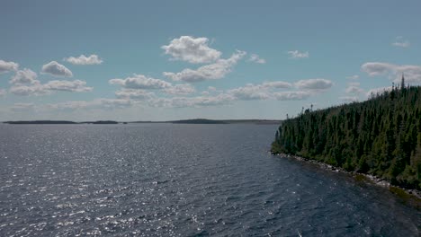 Drone-flying-along-the-shores-of-a-lake-and-forest-on-a-beautiful-summer-day
