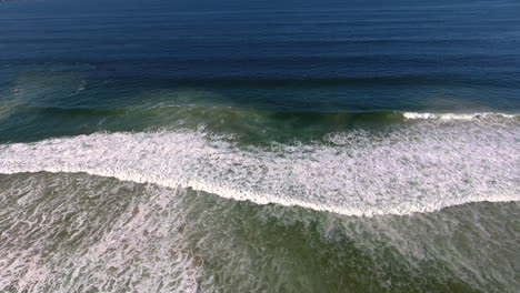 Aerial-drone-view-of-ocean-with-waves-crashing-and-sand-shot-in-4k-high-resolution
