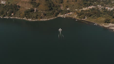 Vista-Aérea-De-Drones-Siguiendo-Un-Transporte-En-Barco-Conduciendo-Sobre-El-Lago-Atitlan-Guatemala