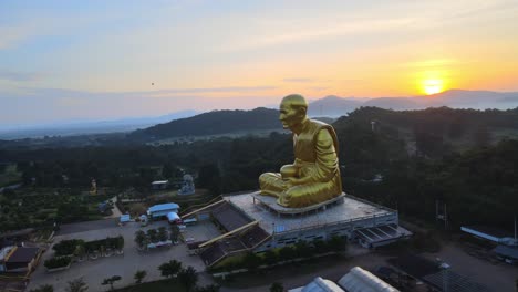 4K-Luftdrohnenaufnahmen-Einer-Riesigen-Mönchsstatue,-Umgeben-Von-Bergen-Von-Khao-Yai-In-Der-Abenddämmerung-In-Thailand