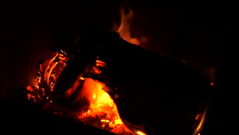 Home-log-wood-fire-burning-in-slow-motion-with-bright-hot-embers,-ash-and-orange-red-flickering-flames