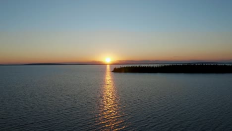 Drone-Moviéndose-Hacia-El-Sol-Poniente-Sobre-Un-Magnífico-Lago-En-El-Norte-De-Canadá