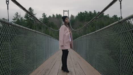 Lovely-Woman-In-Pink-Blazer-And-Black-Bonete-Hat-At-Suspension-Hanging-Bridge-Over-Coaticook-River,-Eastern-Townships,-Quebec-Canada,-Slow-Motion-Shot