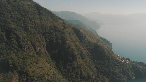 Drone-aerial-flying-next-to-beautiful-green-mountains-in-lake-Atitlan,-Guatemala