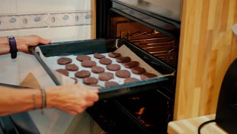Close-up-of-female-arms-putting-cookies-in-the-oven