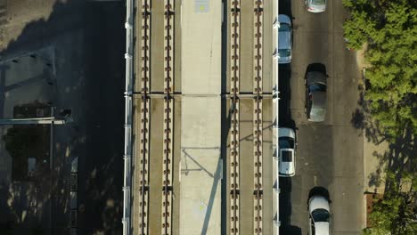 Top-Down-Aerial-View-of-Elevated-Train-Tracks-Over-Urban-Street-with-Cars,-Empty