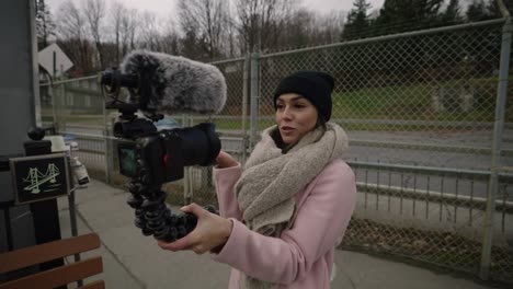 A-Woman-In-Winter-Outfit-Recording-A-Video-With-Her-Handheld-Camera-At-The-Park-In-Coaticook,-Quebec,-Canada---Medium-Shot,-Slow-Motion