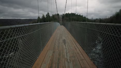 Puente-Suspendido-Más-Largo-Sobre-El-Río-Coaticook-Durante-Un-Día-Nublado-En-Los-Municipios-Del-Este,-Quebec,-Canadá,-Tiro-Inclinado