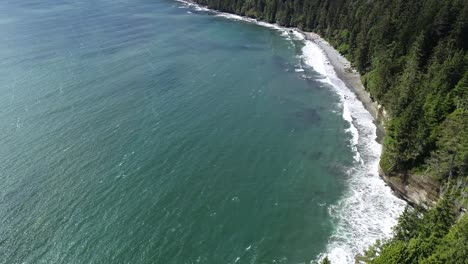 Aerial-View-of-Grey-Sand-Mystic-Beach-and-Green-Conifer-Forest-on-Vancouver-Island-Coastline,-Scenic-Landscape-on-Sunny-Day,-Drone-Shot