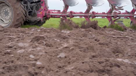 Low-POV-pan-left-shot-of-farm-tractor-plowing-land