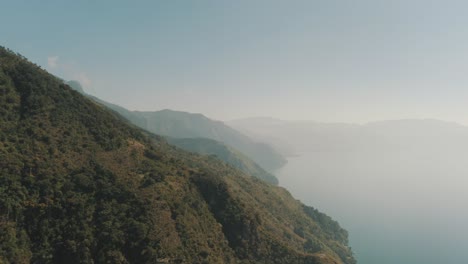 Drone-aerial-flying-over-the-mountains-surrounding-lake-Atitlan,-Guatemala-during-a-cloudy-morning