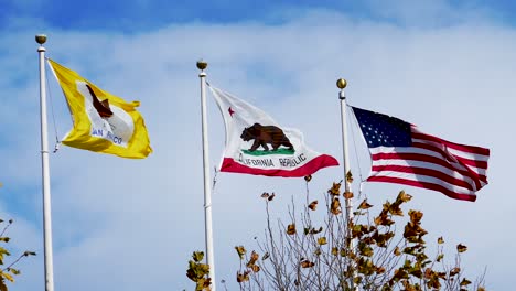 San-Francisco-flag,-California-flag,-and-united-states-flags-on-a-pole-blowing-in-the-strong-wind