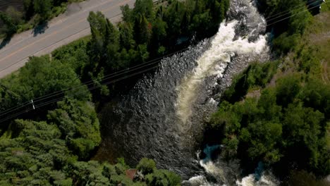 Drone-flying-over-a-rapid-flowing-under-a-bridge-and-then-revealing-the-immensity-of-the-lake-on-a-sunny-day