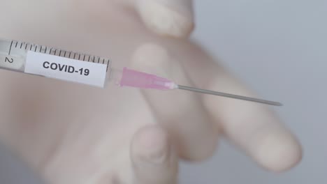 Hand-With-Glove-Flick-Off-The-Syringe-With-Covid-19-Vaccine,-Close-Up-Shot