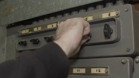 Hand-turning-on-switches-on-old-fuse-box-and-turning-on-lights