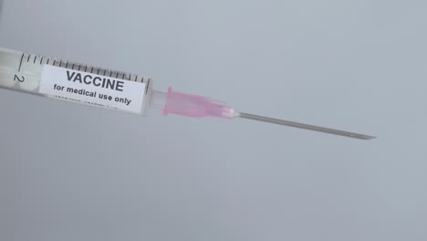 Syringe-With-Vaccine-For-Immunization-Flip-By-A-Finger-With-Glove,-Close-Up