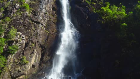 Wasserfall-In-Australien,-Satte-Grüne-Farben,-Die-Von-Der-Morgensonne-Beleuchtet-Werden,-Wasser,-Das-Auf-Die-Felsen-Stürzt