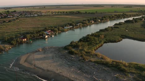 Aerial-shot-of-the-valleys-near-Ravenna-where-the-river-flows-into-the-sea-with-the-typical-fishermen's-huts