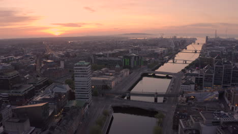 Aerial-view-over-Dublin-City-at-Sunrise,-beautiful-movement-over-the-river-Liffey-in-the-heart-of-the-Irish-capitol