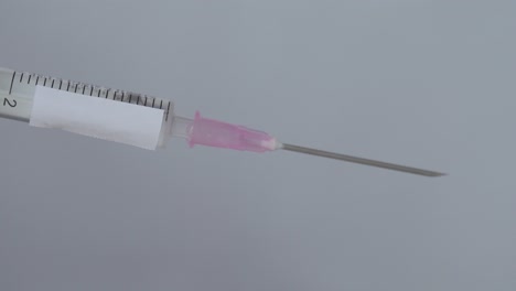 Syringe-For-Vaccination-With-Drops-On-Needle-Being-Flick-By-Finger,-Close-Up
