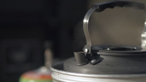 Kettle-boiling-on-gas-camping-stove,-closeup-of-hot-steam