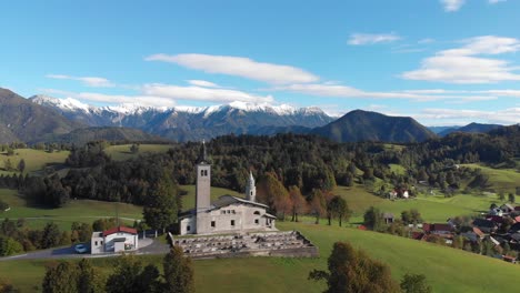 Idyllic-Slovenian-mountains-landscape-St-Marys-historical-church-landmark-aerial-orbit-left