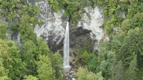 Tall-Wildenstein-Waterfall-in-south-Austrian-alps-over-a-rocky-cliff,-Aerial-dolly-out-reveal-shot