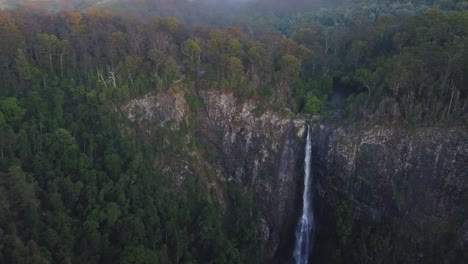 Filmische-Luftaufnahme-Von-Ellenborough-Falls-Im-Morgengrauen,-Die-Sich-Während-Der-Blauen-Stunde-Langsam-Der-Spitze-Der-Wasserfälle-Nähert,-Dunkle-Und-Launische-Landschaftswildnis