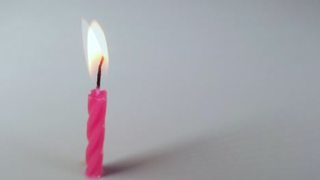 Pink-Birthday-Candle-Melting-On-Grey-Background-Time-lapse