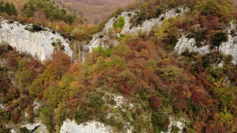 Paradise-mountain-scenery-with-rocks-surrounded-by-yellow-brown-trees-in-Autumn