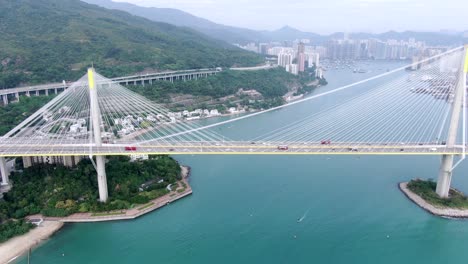 Traffic-on-a-Bridge-in-Hong-Kong-bay-with-city-buildings-in-the-horizon,-Aerial-view
