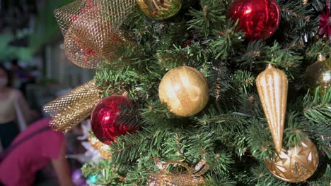 Christmas-tree-gift-red-and-gold-balls-ornament-decorations-are-seen-hang-from-a-decorated-Christmas-pine-tree