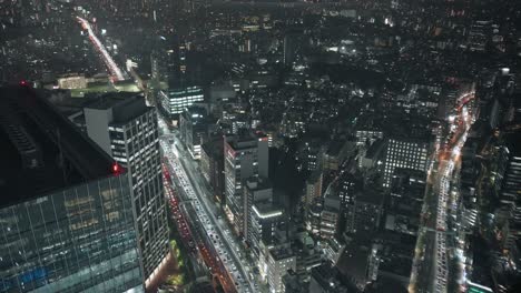 Carretera-Congestionada-Y-Edificios-De-Gran-Altura-Iluminados-En-Shibuya,-Tokio-Por-La-Noche---ángulo-Alto,-En-Tiempo-Real